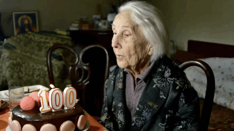 A centenarian blows out her 100th birthday candles. (Photo by Dan Negureanu on Shutterstock)
