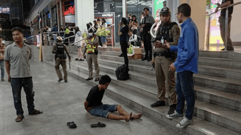 Varakorn Pubthaisong sits on the pavement in front of the Big C shopping centre on Ratchadamri Road in Bangkok after setting fire to two Malaysian tourists on Thursday night. (Photo: Police via Wassayos Ngamkham)