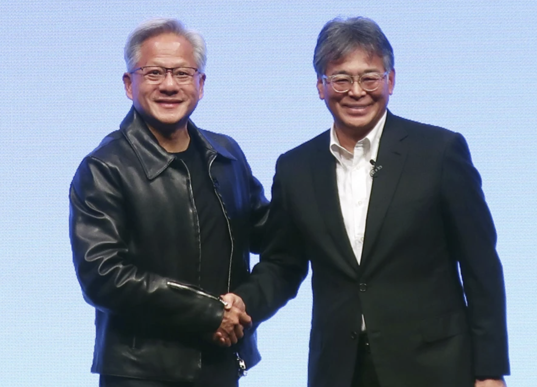 Nvidia Chief Executive Jensen Huang, left, and Fujitsu Chief Executive Takahito Tokita shake hands during an announcement in Tokyo Friday, Oct. 3, 2025. (Kyodo News via AP)